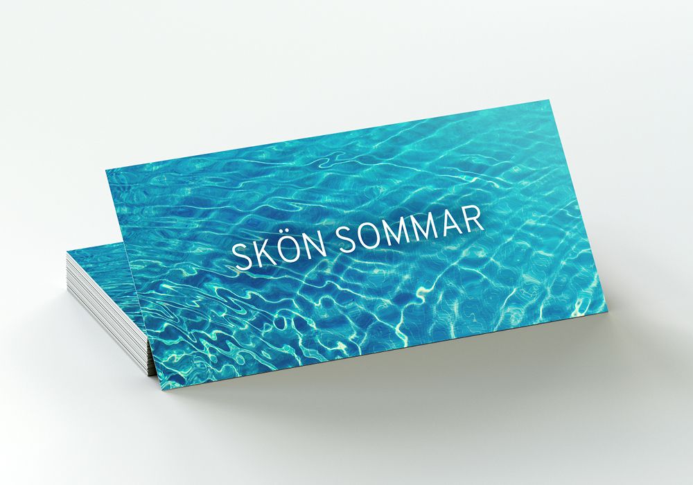 En bild på gåvokort sommarläsning. Gåvokortet har ett bakgrundsmotiv med klarblått vatten och texten Skön Sommar